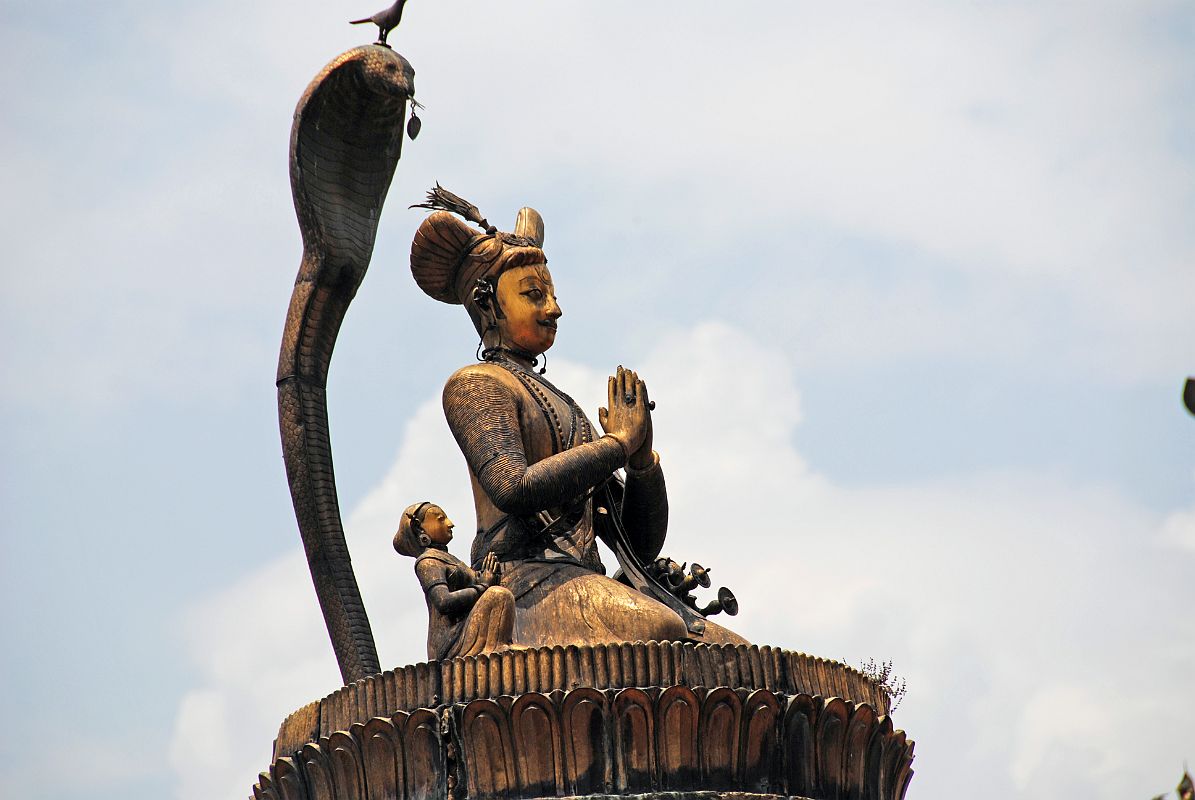 Kathmandu Patan Durbar Square 11 King Yoganarendra Malla Column Close Up The King Yoganarendra Malla column (1700) in Patans Durbar Square is topped by a golden statue of a kneeling King Yoganarendra Malla and his queens on a lotus, protected by the hood of a cobra with a bird on his head.